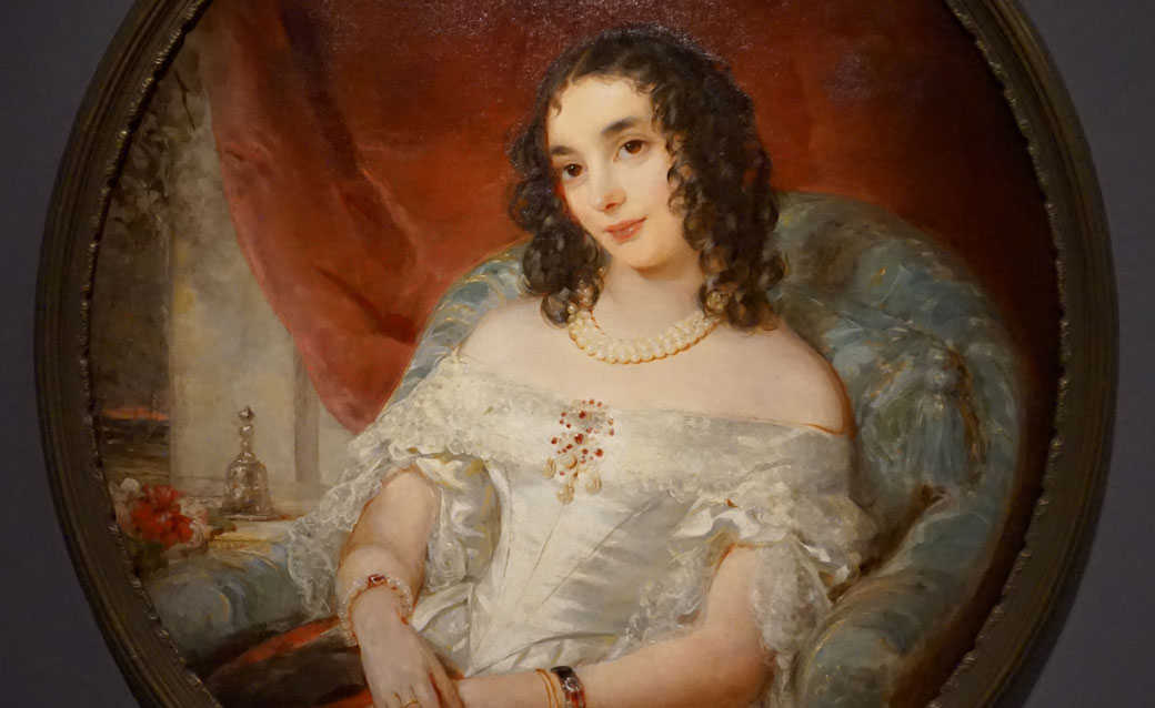 detail of a portrait of a Russian princess by Christina Robertson. She wears a fancy white dress, and her dark hair hangs to her shoulders in ringlets as she sits at leisure in a soft chair.