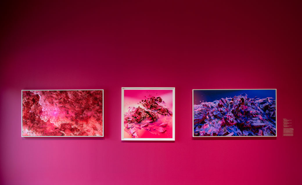 an installation shot of the Nancy Baker Cahill exhibition, with three abstract works of art on a pink wall