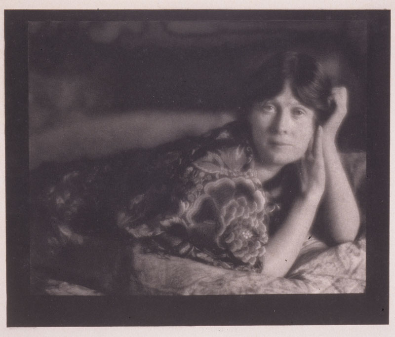 A photograph by Edward Steichen of the dancer Isadora Duncan, seen reclining, with her head resting on her hands, her arms bent, and wearing an embroidered robe
