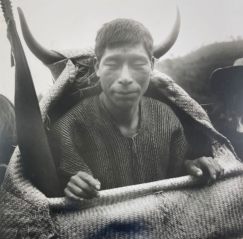 A black and white photograph by Arthur Tress that shows an Indigenous man with close-cropped hair and closed eyes putting on a bull costume in preparation for a dance