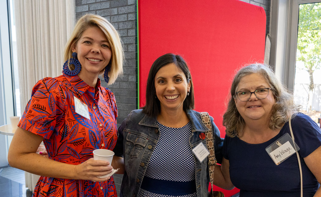Three smiling women with their arms around each other, posing for a photo at last year's Friends Annual Meeting and Friends Appreciation Month Kick-Off event.